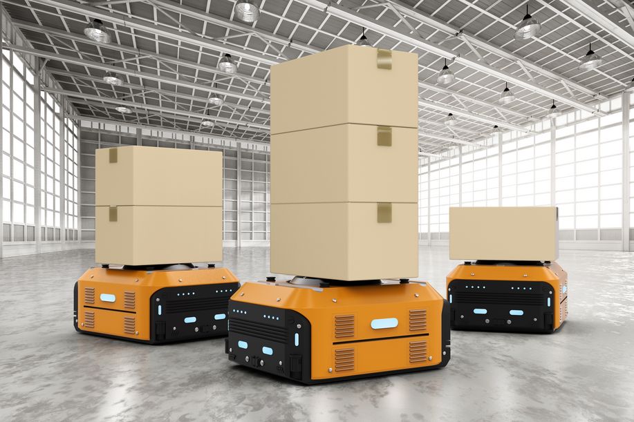 Trois chariots autoguidés orange transportent plusieurs paquets dans un grand entrepôt lumineux