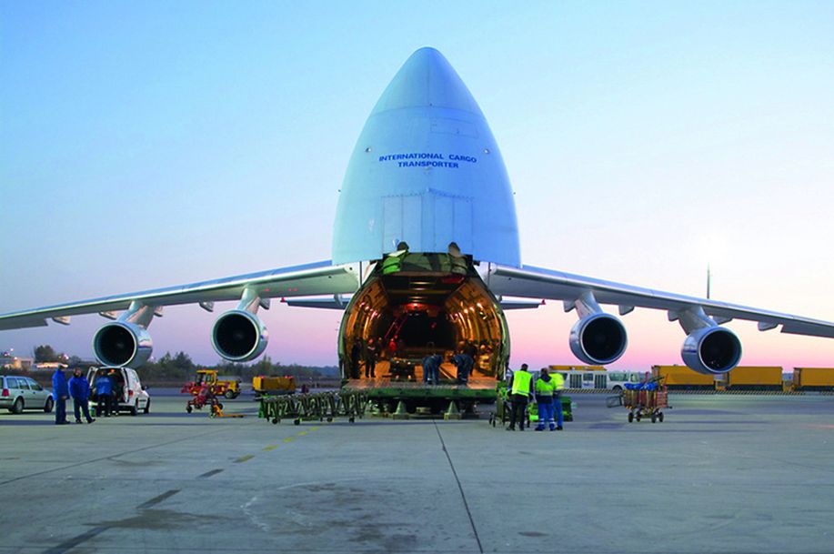 Des employés de l’aéroport chargent la soute d’un avion de fret Antonov à l’aide de tapis roulants sur un terrain d’aviation